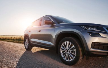 Güneş ışığı otomobilin üzerinden geçer. Gündüz vakti, kırsal kesimde yan yola park edilmiş modern yeni bir araba..