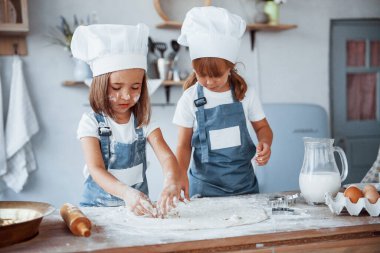Yemek pişirmeye odaklan. Beyaz şef üniformalı aile çocukları mutfakta yemek hazırlıyorlar..