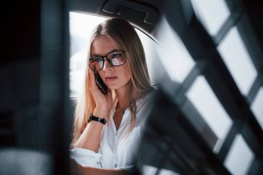 Yansımalar yanda. Zeki iş kadını, siyah iç mekanı olan lüks arabanın arka koltuğunda oturur..