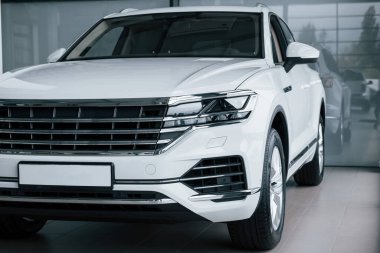 Arkasında gri cam var. Gündüz vakti park edilmiş modern lüks beyaz arabanın parçacık görüntüsü.