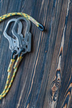 Yeni başlayanlar ve profesyoneller için iyi. Tırmanma ekipmanlarının izole edilmiş fotoğrafı. Karabinanın bir parçası ahşap masada yatıyor..