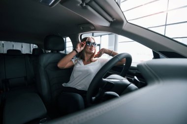 Güneş gözlüğü takıyordu. Modern arabadaki kız kuaförde. Gündüz vakti. Yeni araç alınıyor.