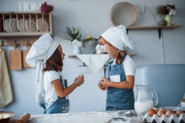 Süreç boyunca eğleniyorum. Beyaz şef üniformalı aile çocukları mutfakta yemek hazırlıyorlar..