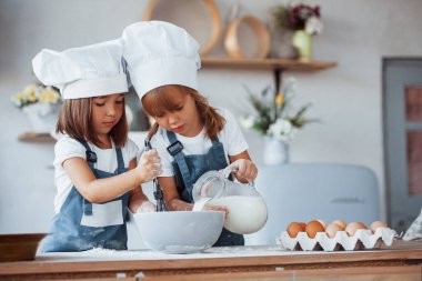 Beyaz şef üniformalı aile çocukları mutfakta yemek hazırlıyorlar..