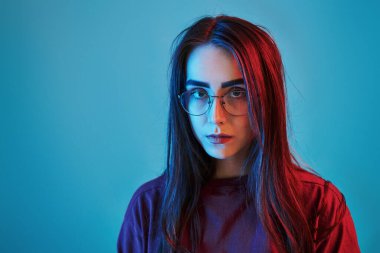 Ciddi bir bakış. Stüdyo içeride neon ışıkla çekiliyor. Güzel bir genç kızın portresi.