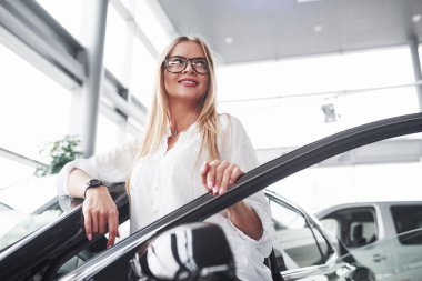 Göz giysisiyle. Tamirhanedeki genç müdür mükemmel cilalanmış siyah arabaya karşı duruyor..