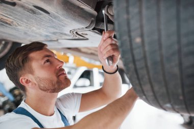 Bu güzel olacak. Mavi üniformalı işçi otomobil salonunda çalışıyor..