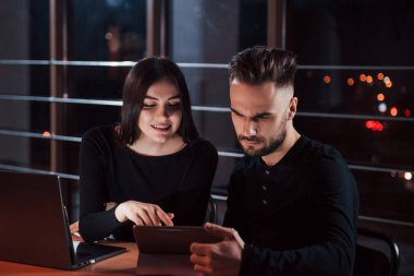 Küçük şehir ışıkları pencereden içeri giriyor. Genç iş adamlarından oluşan bir ekip gece ofiste projeleri üzerinde çalışıyor..