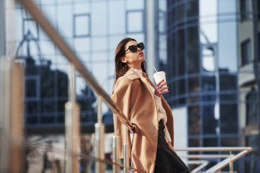 Duruyor ve gün ışığından zevk alıyor. Kalın elbiseli genç bir kız hafta sonları şehirde yürür..