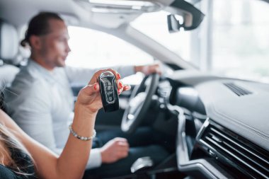 Kadının elinde siyah renkli anahtarlar var. Yeni arabanın özelliklerini bayan müşteriye gösteren pozitif yönetici.