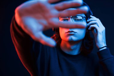 Uzamış ellerle. Stüdyo karanlık stüdyoda neon ışıkla çekiliyor. Ciddi bir adamın portresi..