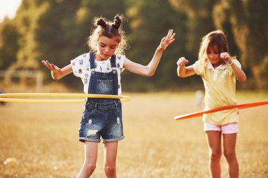 Daire şeklinde spor aletleri olan kızlar. Bir grup çocuğun sahada aktif bir hafta sonu var..