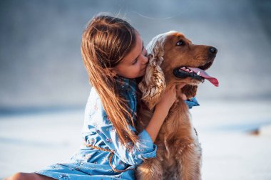 Evcil hayvanı kucaklamak. Şirin küçük kız, güneşli bir günde köpeğiyle dışarı çıkar..