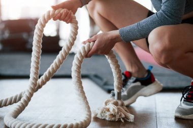 Elinde özel beyaz bir ip var. Sportif genç bir kadın sabah spor salonunda spor yapıyor..