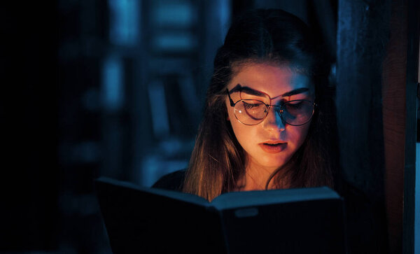 Свет идет из книги. Студентка в библиотеке. Концепция образования.