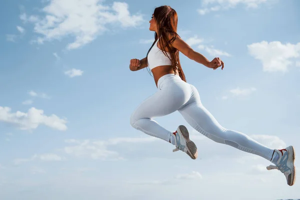 在天空中 身穿白色运动服的女赛跑选手健身 — 图库照片