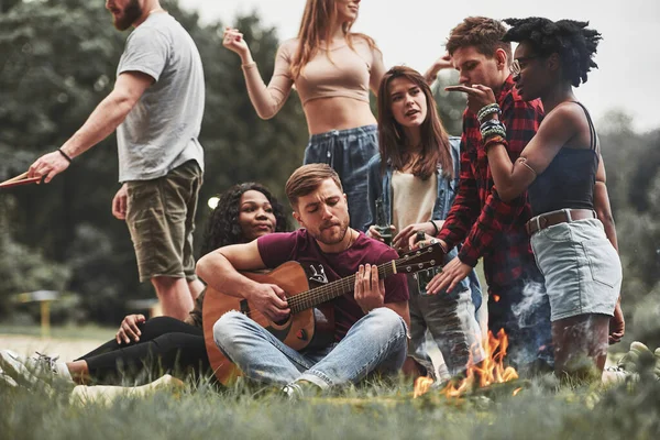 Gitarzysta Stara Się Jak Może Grupa Ludzi Organizuje Piknik Plaży — Zdjęcie stockowe