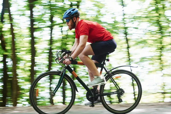 速度真快晴天 骑自行车的人在森林里的柏油路上 — 图库照片
