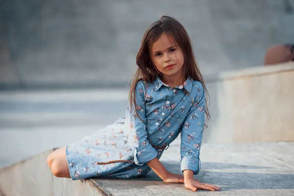 Mała Dziewczynka Niebieskim Stroju Pozowanie Kamery Mieście Gdy Opiera Się — Zdjęcie stockowe
