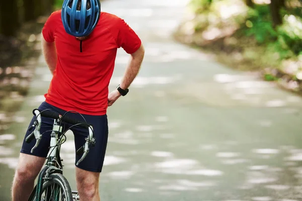 准备搭便车晴天 骑自行车的人在森林里的柏油路上 — 图库照片