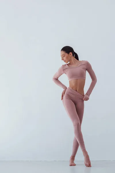 Photo in full height. Caucasian pretty woman doing exercises against white background in the studio.