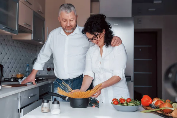 簡単だ 台所で野菜を使った料理を作る白いシャツを着た男と妻 — ストック写真