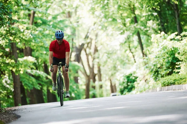 Lekkich Ciuchach Rowerzysta Rowerze Jest Asfaltowej Drodze Lesie Słoneczny Dzień — Zdjęcie stockowe