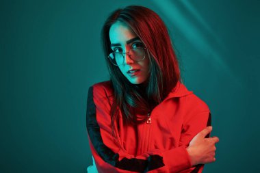 Yeşil arka plana karşı. Stüdyo içeride neon ışıkla çekiliyor. Güzel bir genç kızın portresi.