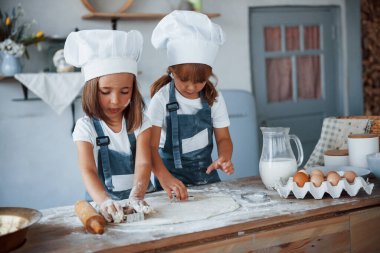 Beyaz şef üniformalı aile çocukları mutfakta yemek hazırlıyorlar..
