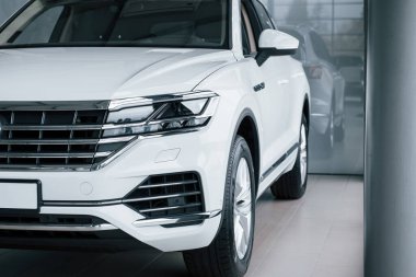 Kesilmiş fotoğraf. Gündüz vakti park edilmiş modern lüks beyaz arabanın parçacık görüntüsü.