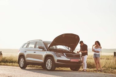 Araba tamir edildiğinde beklemek. Adam kıvırcık saçlı bir kızın arabasını tamir ediyor. Mekanik yardım.