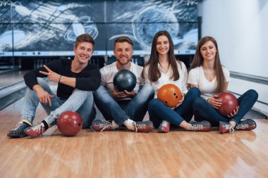 Yerde oturuyordum. Genç neşeli arkadaşlar hafta sonları bowling kulübünde eğleniyorlar..