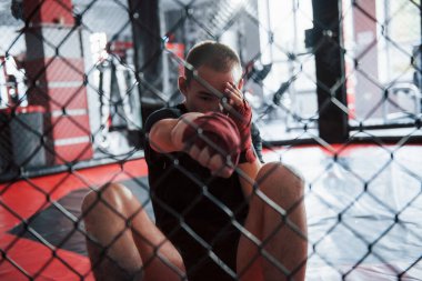 Aşağıdan. Kırmızı bandajlı genç boksör egzersiz yapıyor. Spor salonunda, kafeste..