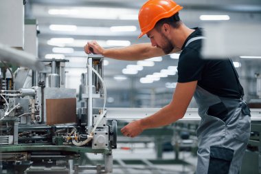 Makine operatörü. Fabrikada sanayi işçisi. Turuncu şapkalı genç teknisyen..