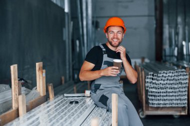 Bir bardak içkiyle. Yemek molası. Fabrikada sanayi işçisi. Turuncu şapkalı genç teknisyen..