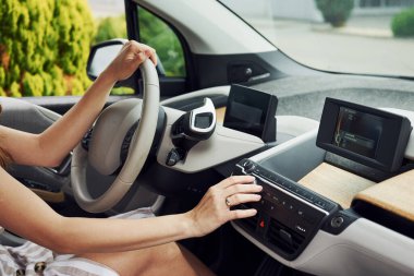 Düğmeyi çeviriyor. Modern otomobilin içindeki kadın sürücü. Yepyeni araba deneniyor.