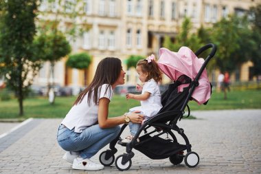 Pembe bebek arabalı güzel anne ve küçük kızı şehirde yürüyüşe çıktılar..