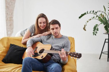 Akort alıyorum. Yeni evin oturma odasında kız arkadaşına akustik gitar çalmak..