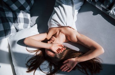 Güneşli güzel bir gün olacak. Güzel genç bir kadın, sabahları yatağında uzanıyor..