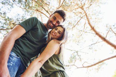 Aşağıdan bak. Yüksek ağaçlar. Genç ve güzel bir çift gündüz vakti ormanda iyi vakit geçirir..