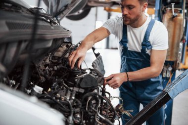 Arabanın motoru. Mavi üniformalı işçi otomobil salonunda çalışıyor..