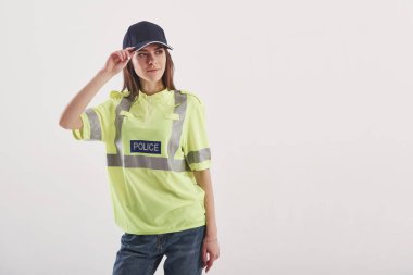 Sıradan kotla. Yeşil polis üniformalı güzel kadın stüdyoda beyaz arka plana karşı duruyor..