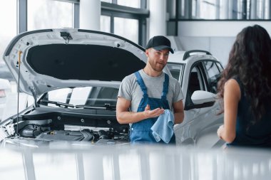 Tamir ettiğim şeyi. Otomobil kuaföründe mavi üniformalı bir kadın tamir edilmiş arabasını geri alıyor..