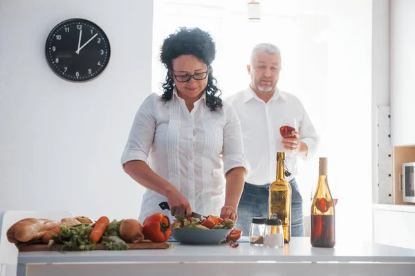 夫を探してる 台所で野菜を使った料理を作る白いシャツを着た男と妻 — ストック写真