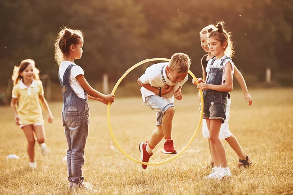 Jumping through the circle fitness tool. Kids having fun in the field.