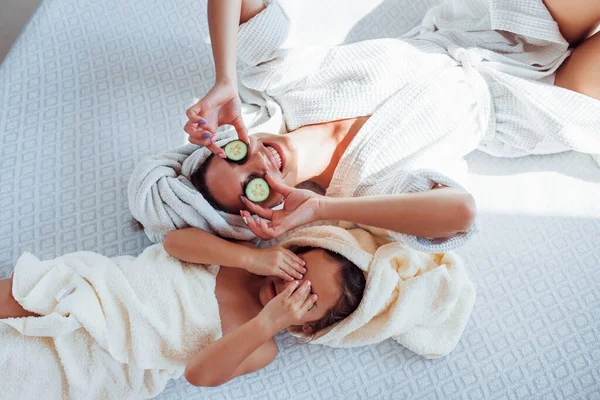 年轻的母亲和女儿头戴毛巾 头戴黄瓜 躺在床上 — 图库照片