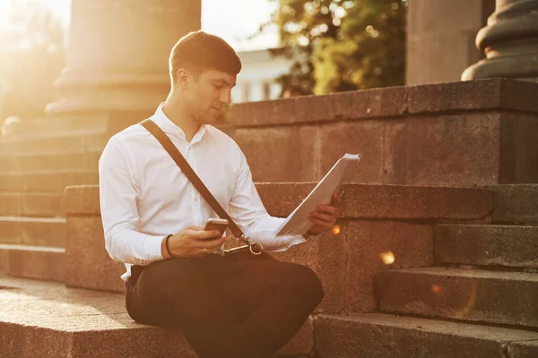 Güneş ışığıyla aydınlatılmış. Resmi giysileri olan bir iş adamı şehirde..
