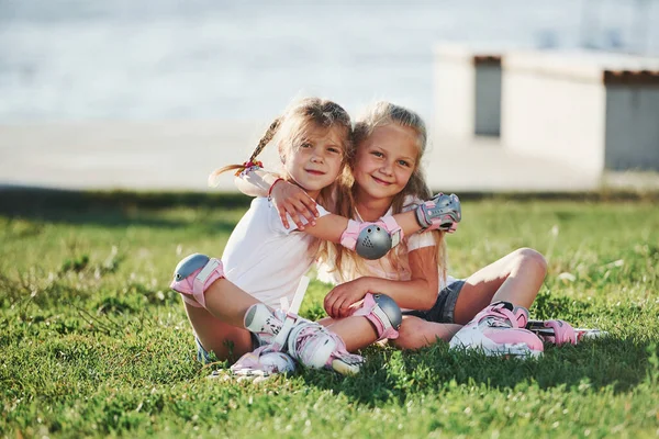 Kids Embracing Sitting Grass Park Roller Skates — Stock Photo, Image