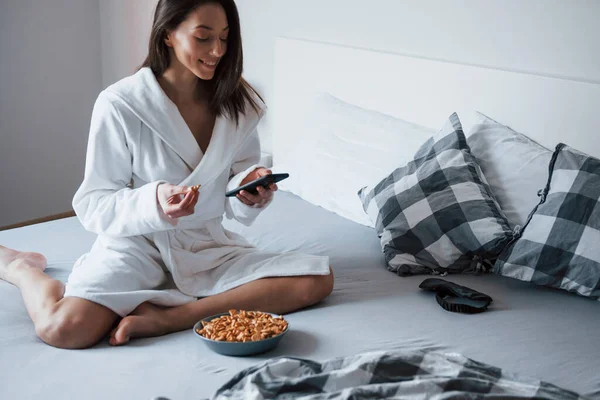 Sitting Bed Using Smartphone Eating Cookies — Stock Photo, Image
