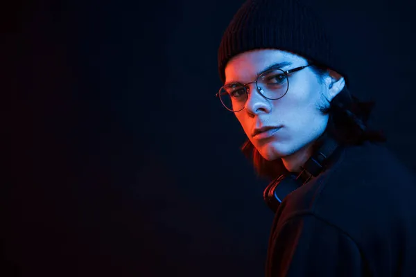 In black hat. Studio shot in dark studio with neon light. Portrait of serious man.